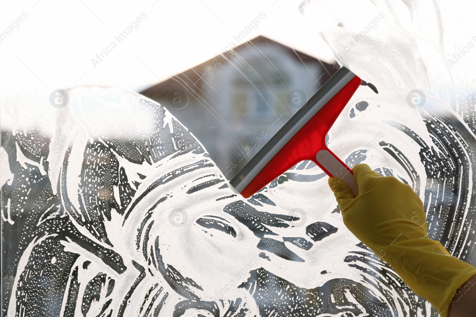 Photo of Woman cleaning window with squeegee indoors, closeup