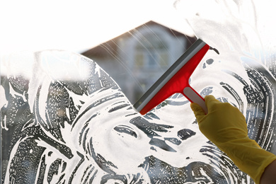 Photo of Woman cleaning window with squeegee indoors, closeup