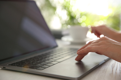 Photo of Woman working with modern laptop at white wooden table, closeup