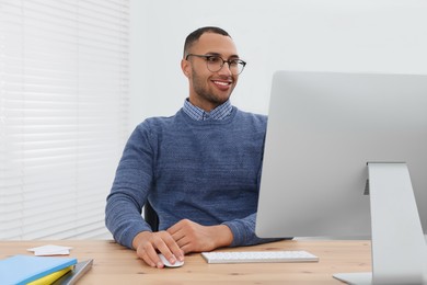 Photo of Happy young intern working with computer in modern office