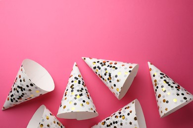 Beautiful party hats on pink background, top view. Space for text