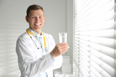 Photo of Nutritionist with glass of water near window in office. Space for text