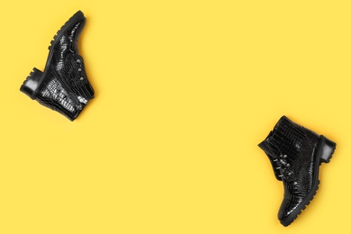 Pair of stylish ankle boots on yellow background, top view. Space for text