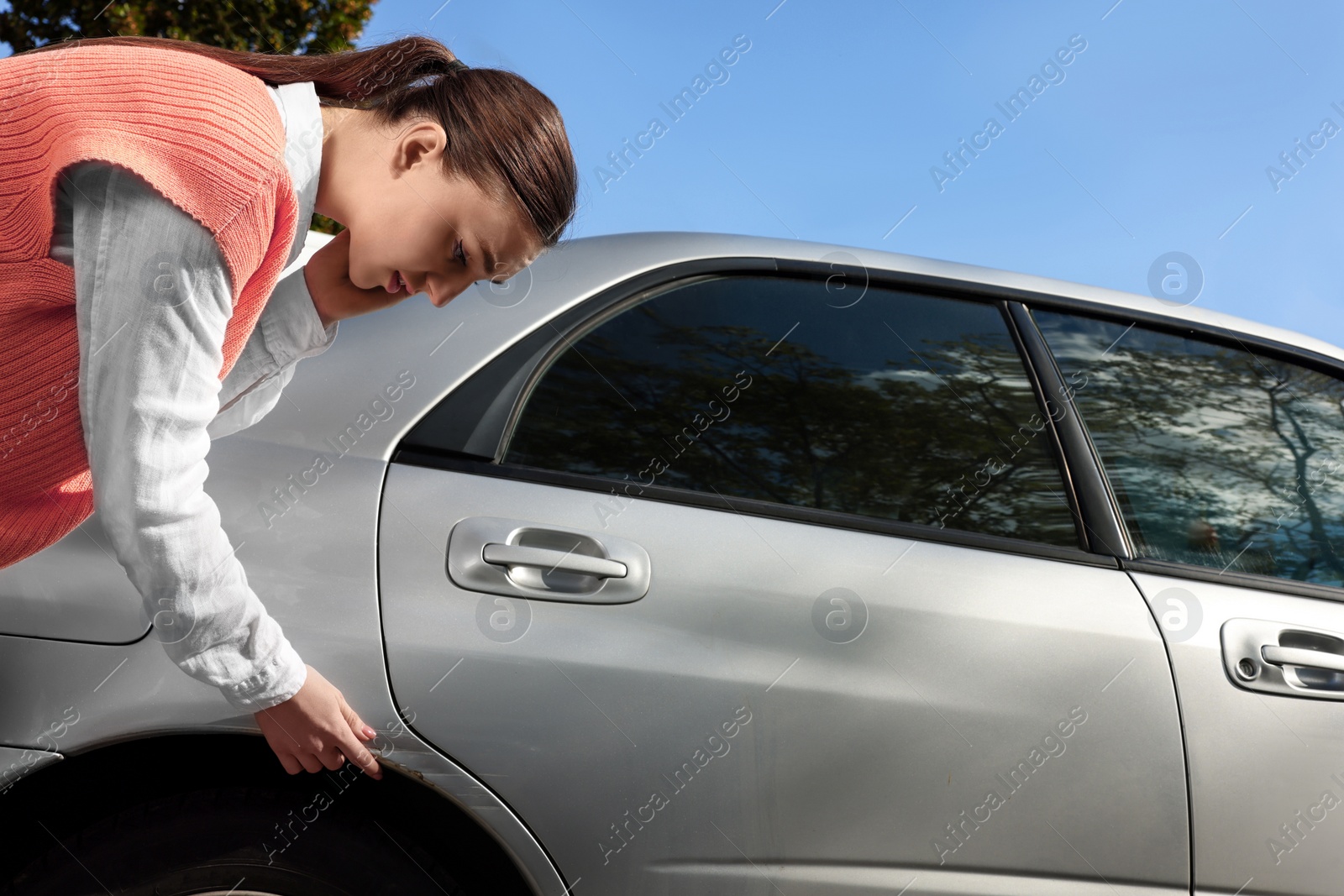 Photo of Stressed woman near car with scratch outdoors