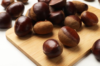 Photo of Sweet fresh edible chestnuts on white table, closeup
