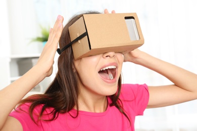 Young woman using cardboard virtual reality headset at home