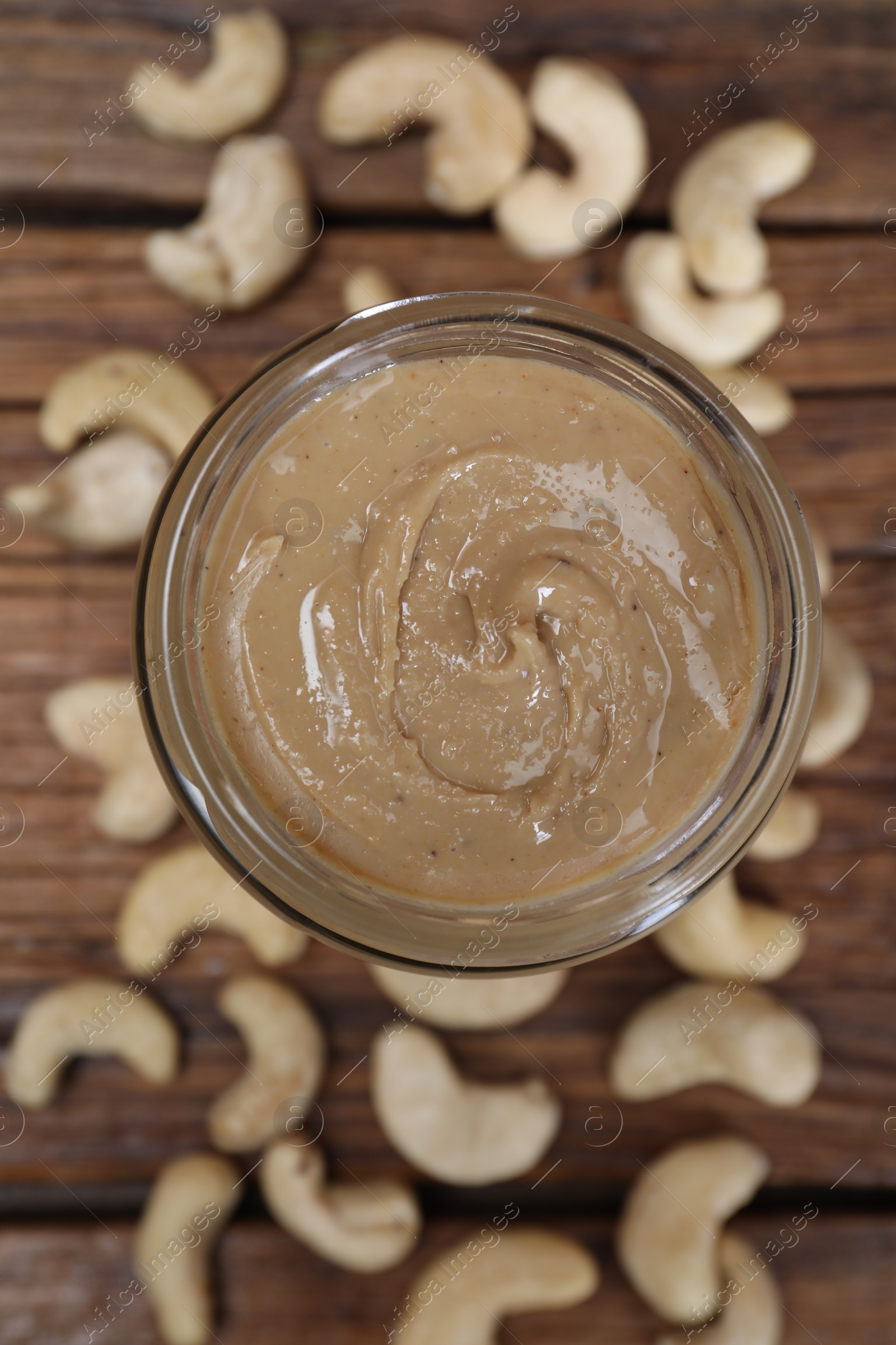 Photo of Tasty cashew nut paste in jar on wooden table, top view