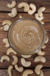 Tasty cashew nut paste in jar on wooden table, top view