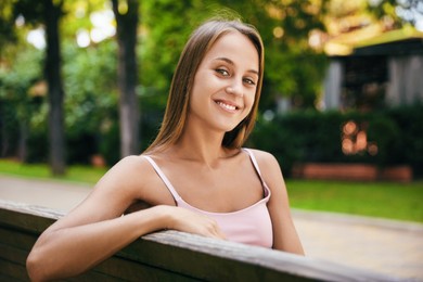 Photo of Beautiful young woman sitting on bench in park