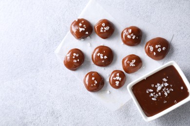 Photo of Tasty candies, caramel sauce and salt on light grey table, top view. Space for text