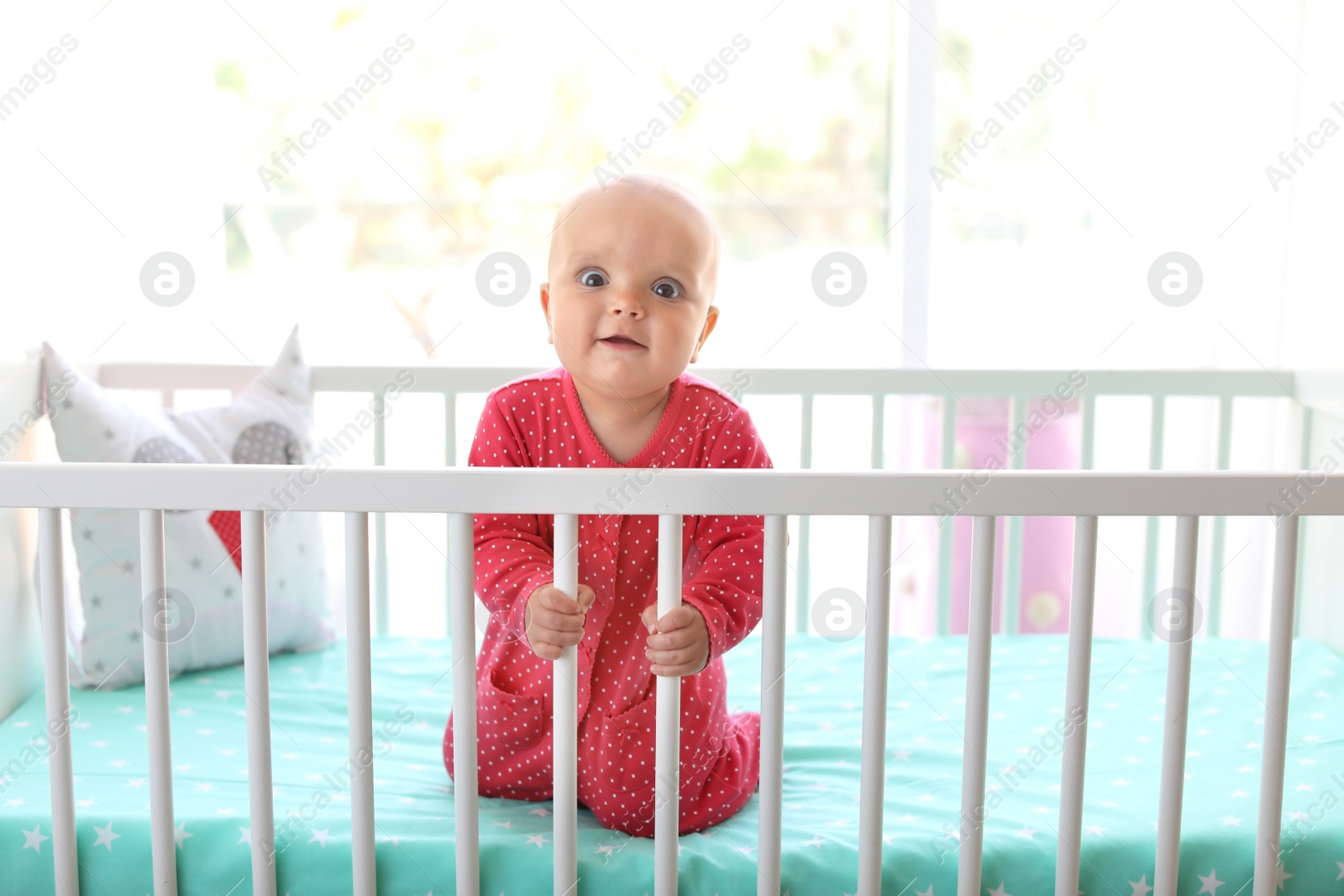 Photo of Cute baby girl in crib at home