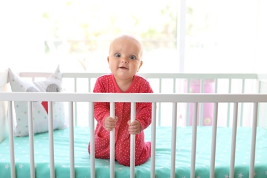 Cute baby girl in crib at home