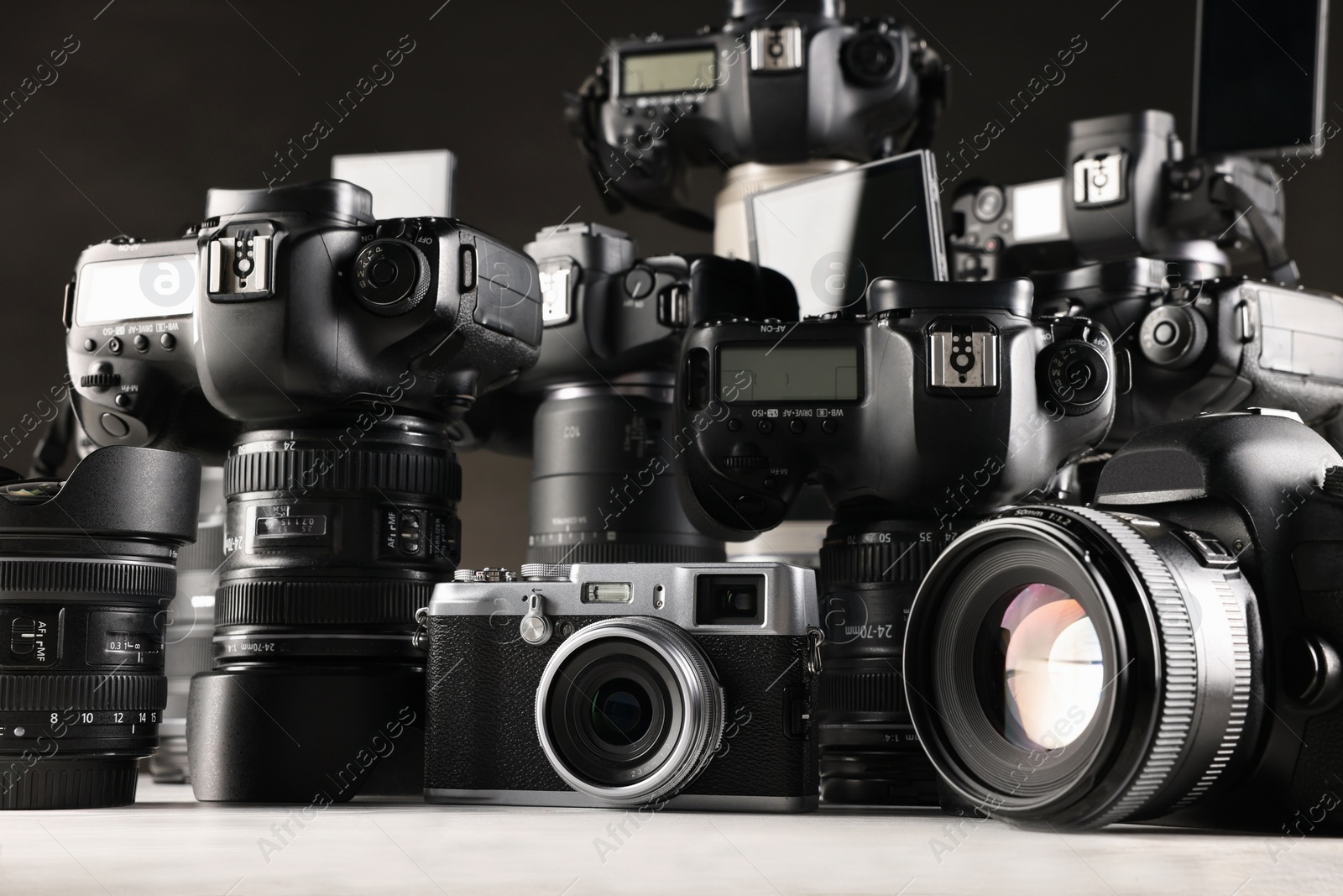 Photo of Modern cameras on white wooden table, closeup