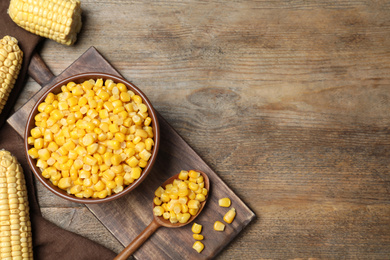 Delicious canned corn in bowl on wooden table, flat lay. Space for text