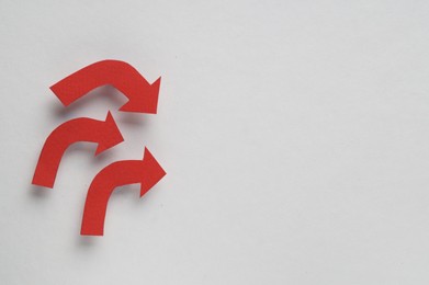 Photo of Red paper arrows on white background, top view. Space for text