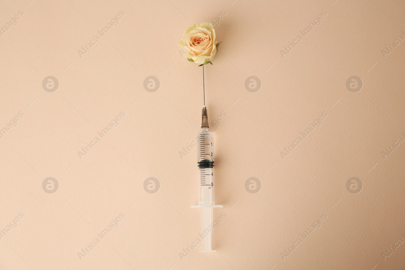 Photo of Medical syringe and beautiful rose on beige background, top view