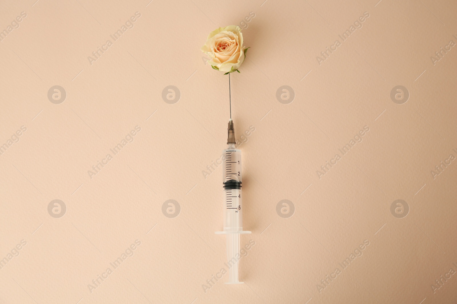 Medical syringe and beautiful rose on beige background, top view Photo of Medical syringe and beautiful rose on beige background, top view
