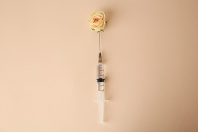 Photo of Medical syringe and beautiful rose on beige background, top view