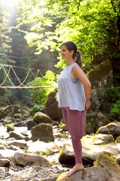 Happy young woman doing morning exercise in mountains