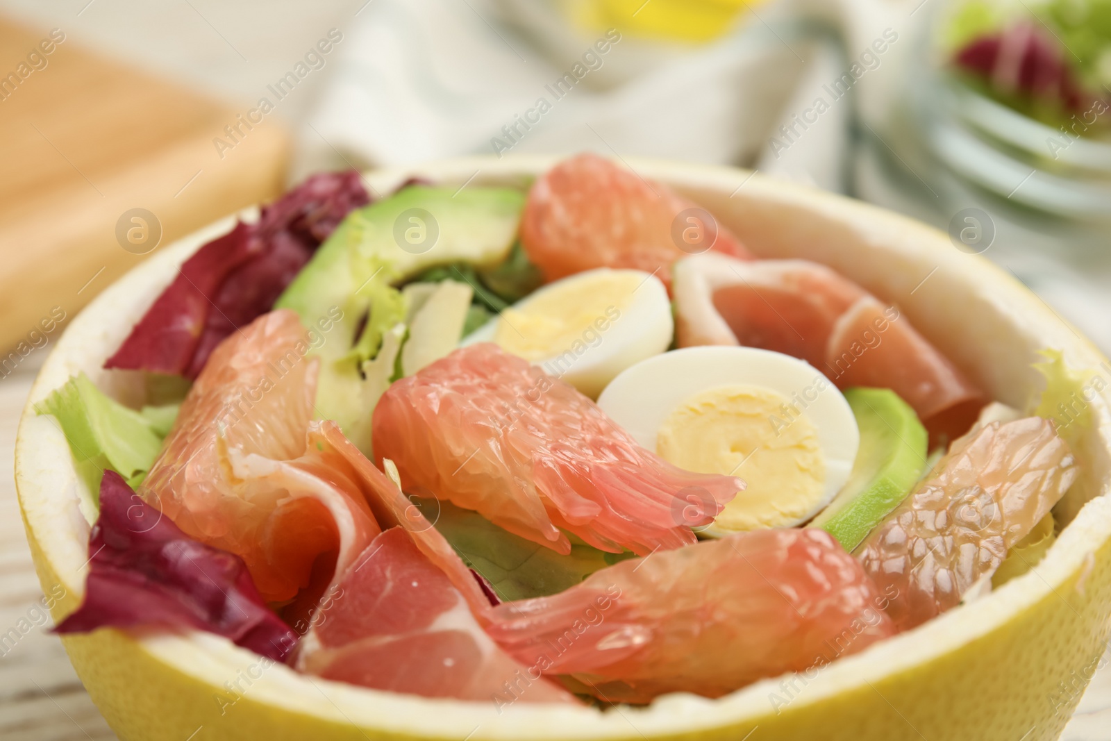 Photo of Delicious pomelo salad with prosciutto in half of fruit, closeup