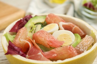 Photo of Delicious pomelo salad with prosciutto in half of fruit, closeup