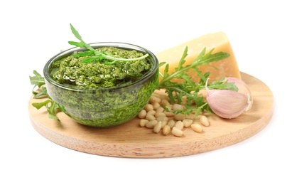 Bowl of tasty arugula pesto and ingredients on white background