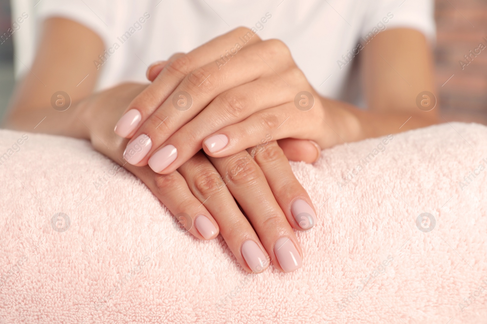 Photo of Woman showing neat manicure on towel, closeup. Spa treatment