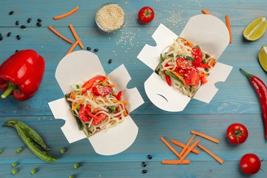 Boxes of vegetarian wok noodles with ingredients on light blue wooden table, flat lay