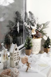 Photo of Beautiful Christmas decorations and small fir trees on window sill indoors