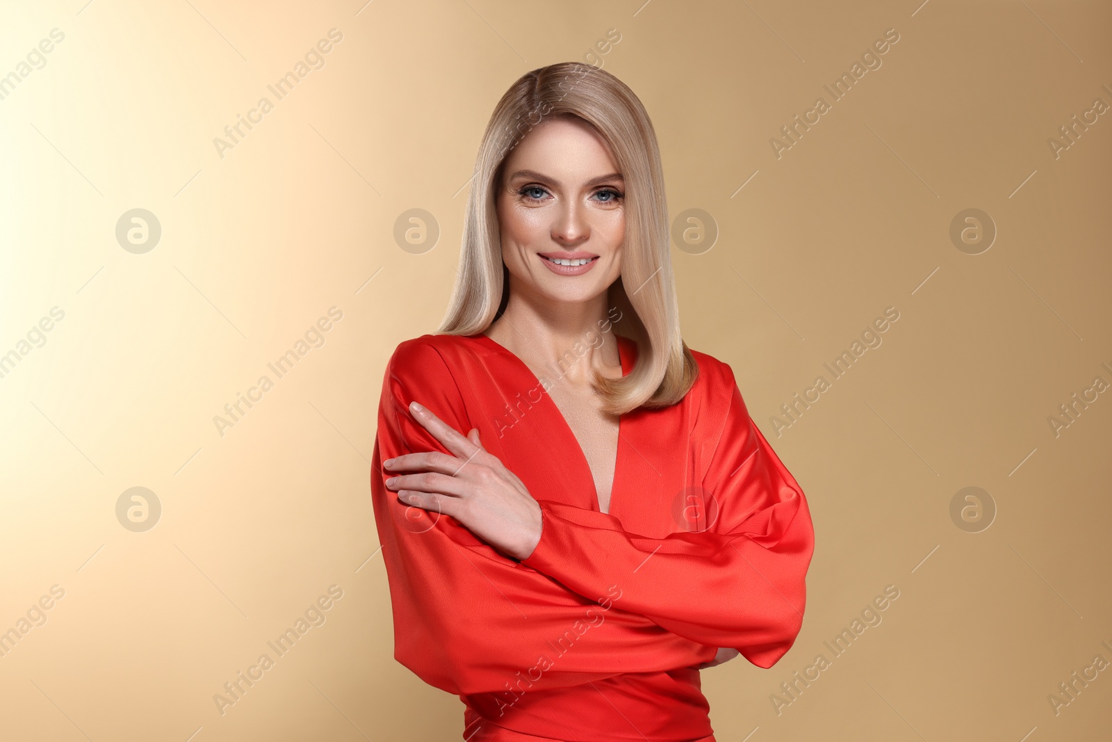 Image of Portrait of stylish attractive woman with blonde hair smiling on dark beige background