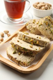 Photo of Tasty halva with pistachios served on white marble table, closeup