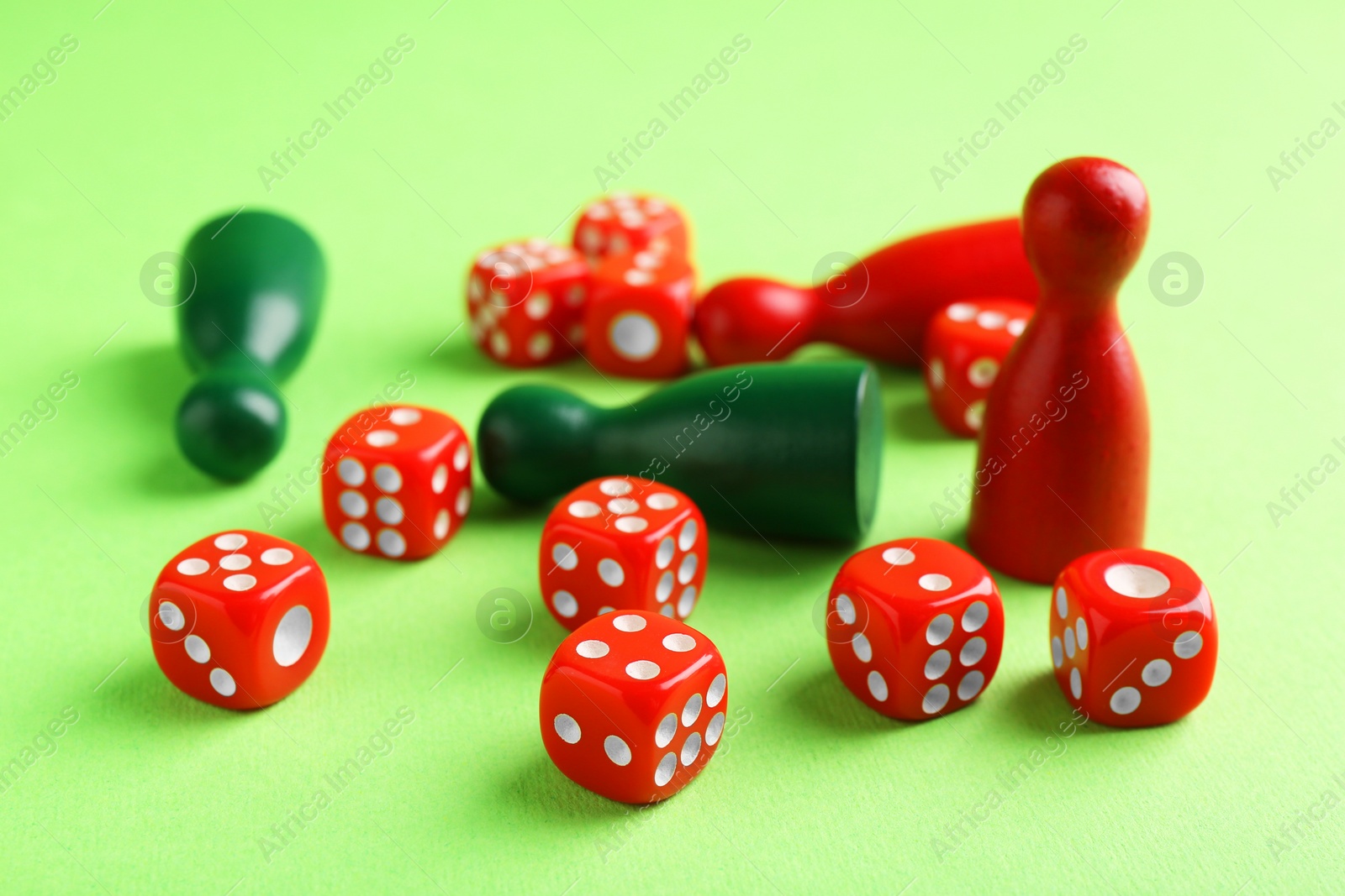 Photo of Many red dices and color game pieces on green background