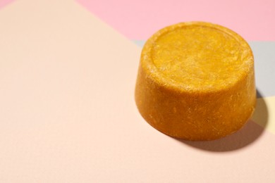 Photo of Orange solid shampoo bar on color background, closeup. Space for text