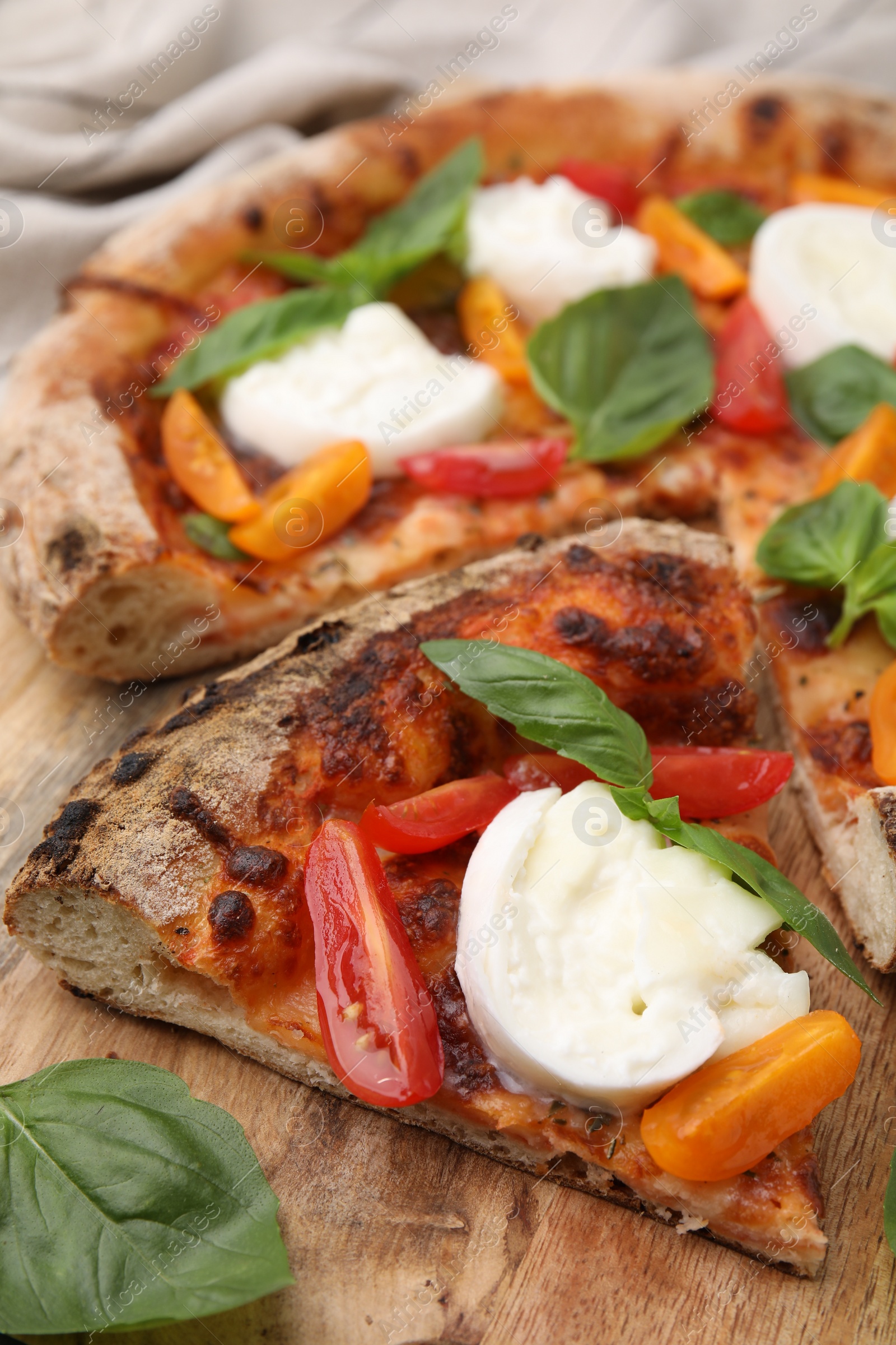 Photo of Slice of delicious pizza with burrata cheese, tomatoes and basil on wooden board, closeup