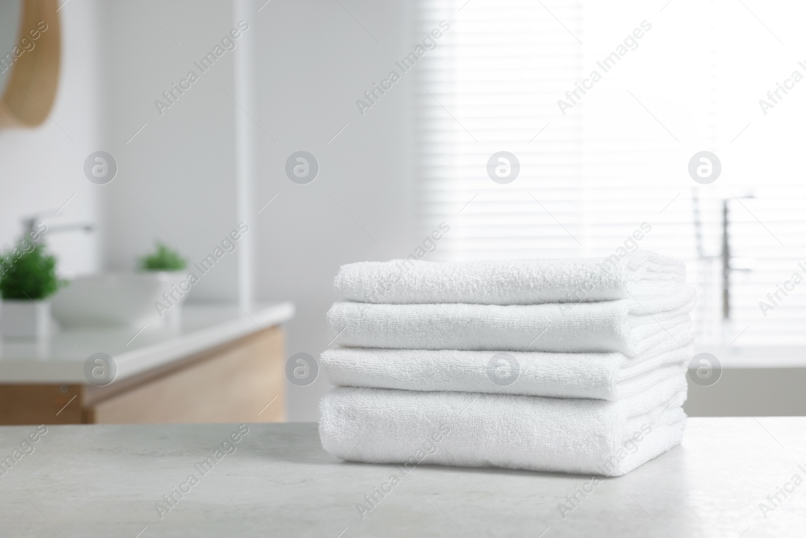 Photo of Stack of white towels on table in bathroom. Space for text