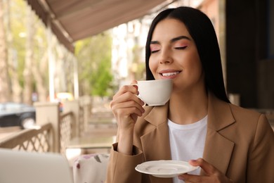 Photo of Woman with cup of aromatic coffee at outdoor cafe in morning