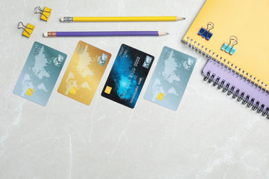 Photo of Credit cards and stationery on light grey marble background, flat lay. Space for text