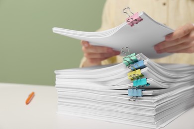 Photo of Woman stacking documents at white table against green background, closeup