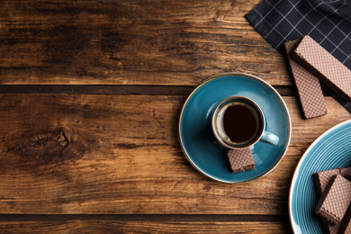 Photo of Breakfast with delicious wafers and coffee on wooden table, flat lay. Space for text