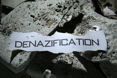 Paper with word Denazification on pieces of concrete, closeup