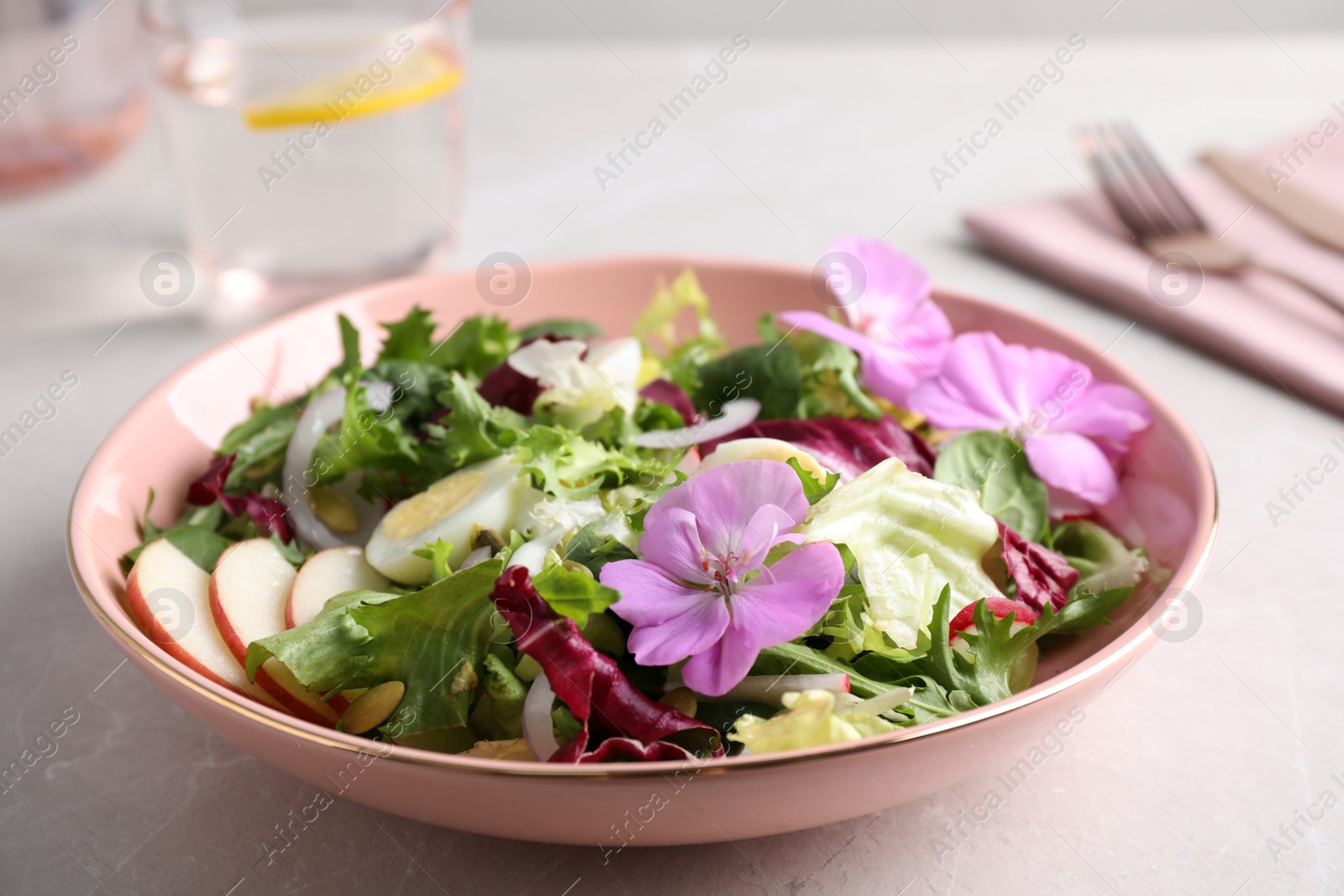 Photo of Fresh spring salad with flowers on grey table, closeup