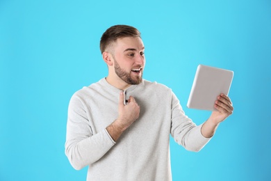 Young man using video chat on tablet against color background