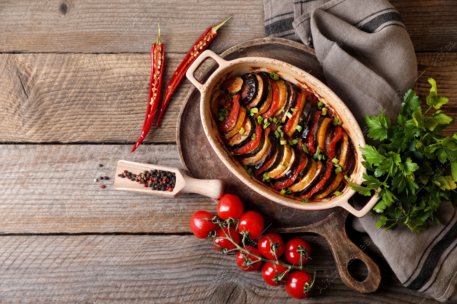 Photo of Delicious ratatouille and ingredients on wooden table, flat lay. Space for text