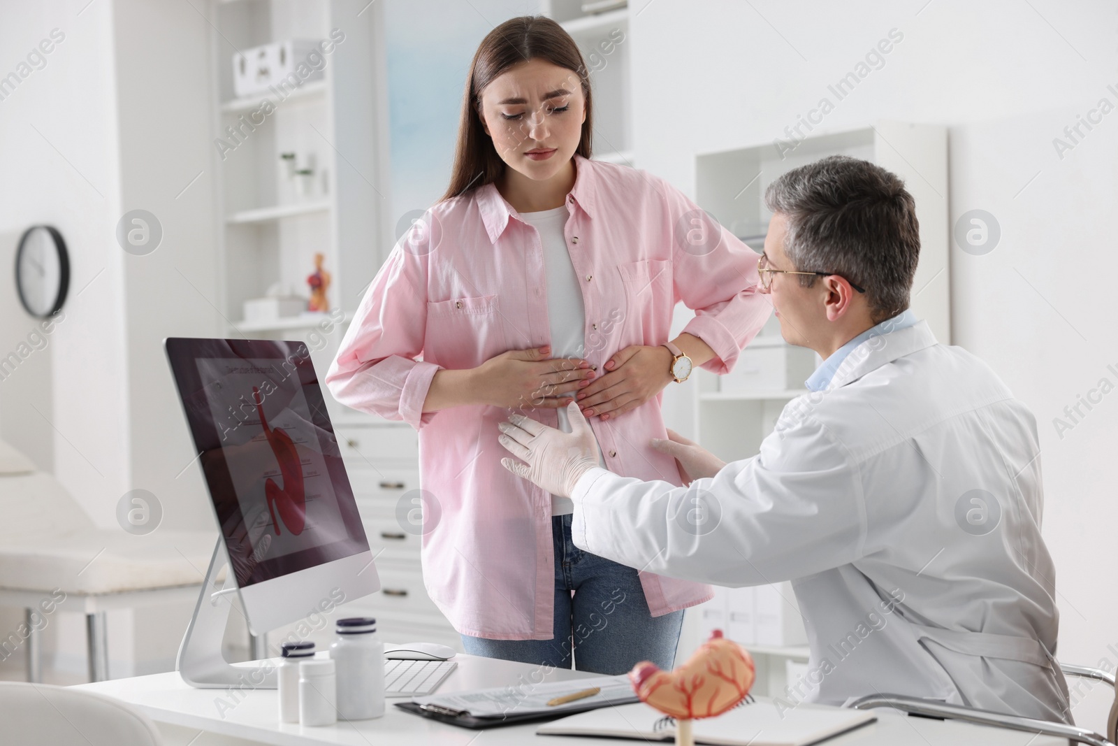 Photo of Gastroenterologist examining patient with stomach pain in clinic