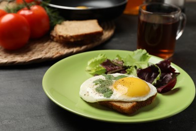 Photo of Delicious breakfast with fried egg and salad served on black table, closeup