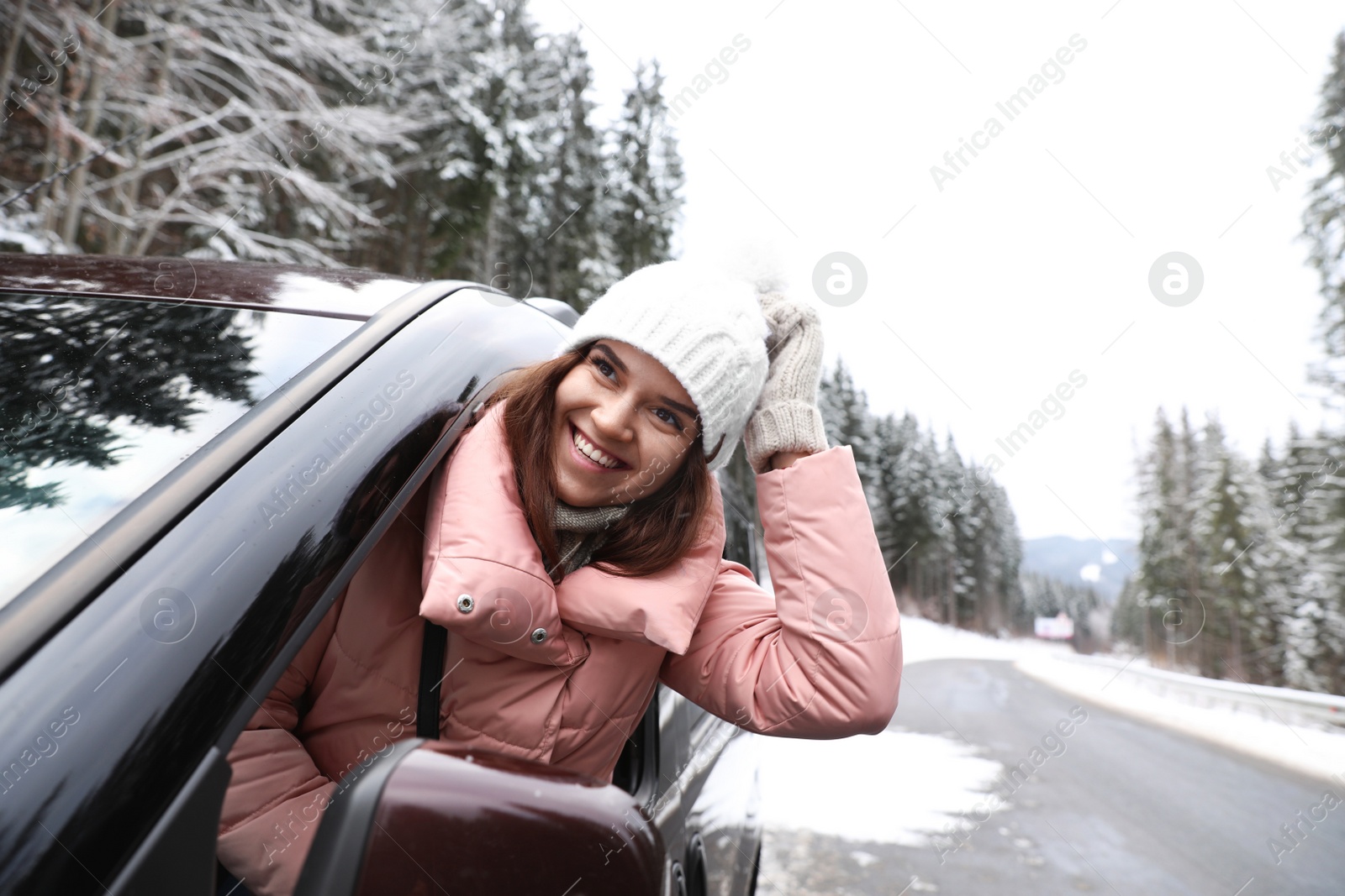 Photo of Young woman looking out of car window on road. Winter vacation