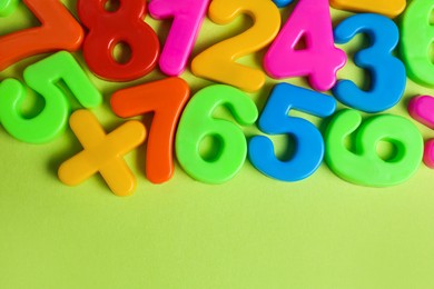 Photo of Colorful magnetic numbers on light green background, flat lay