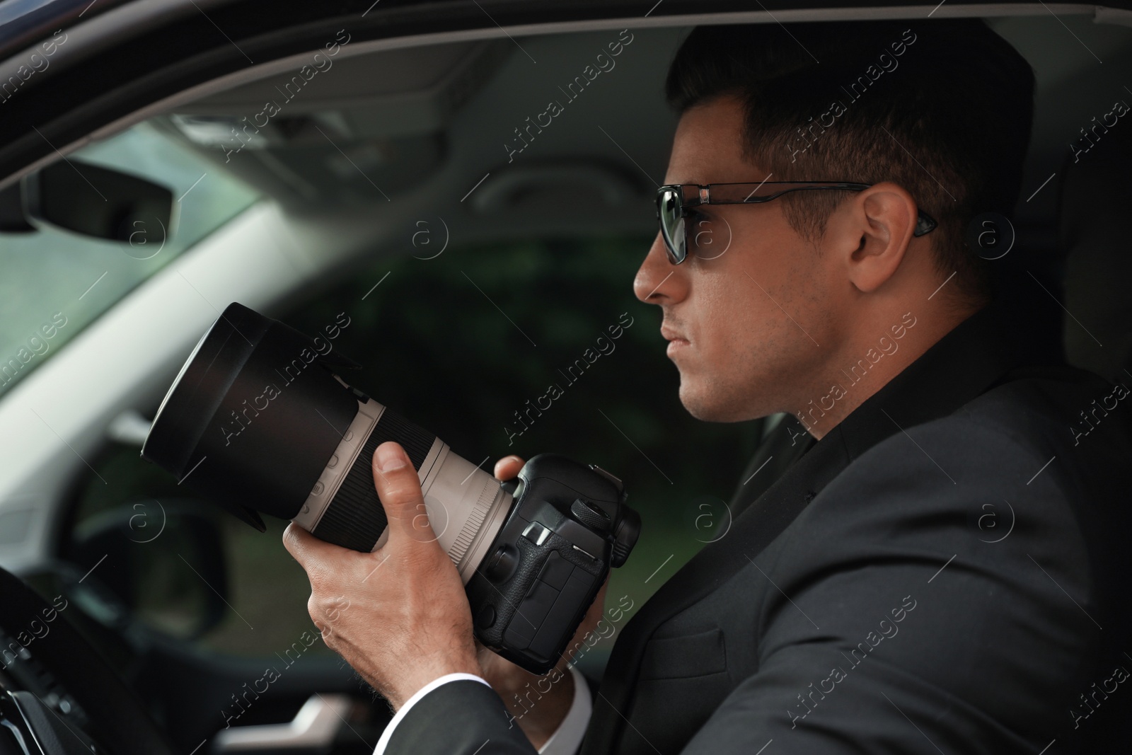 Photo of Private detective with camera spying from car