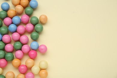 Many bright chewy gumballs on beige background, flat lay. Space for text