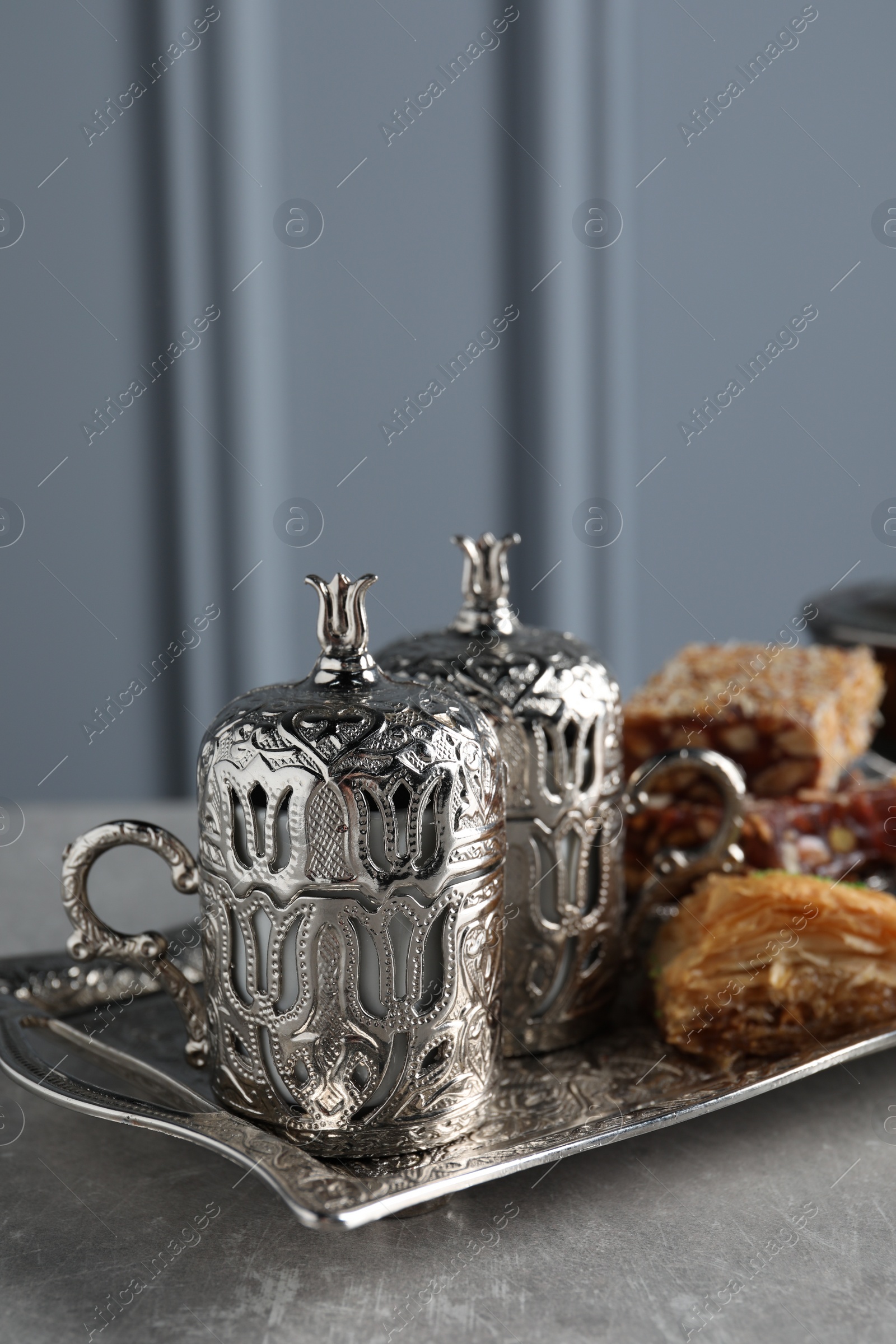 Photo of Tea, baklava dessert and Turkish delight served in vintage tea set on grey textured table